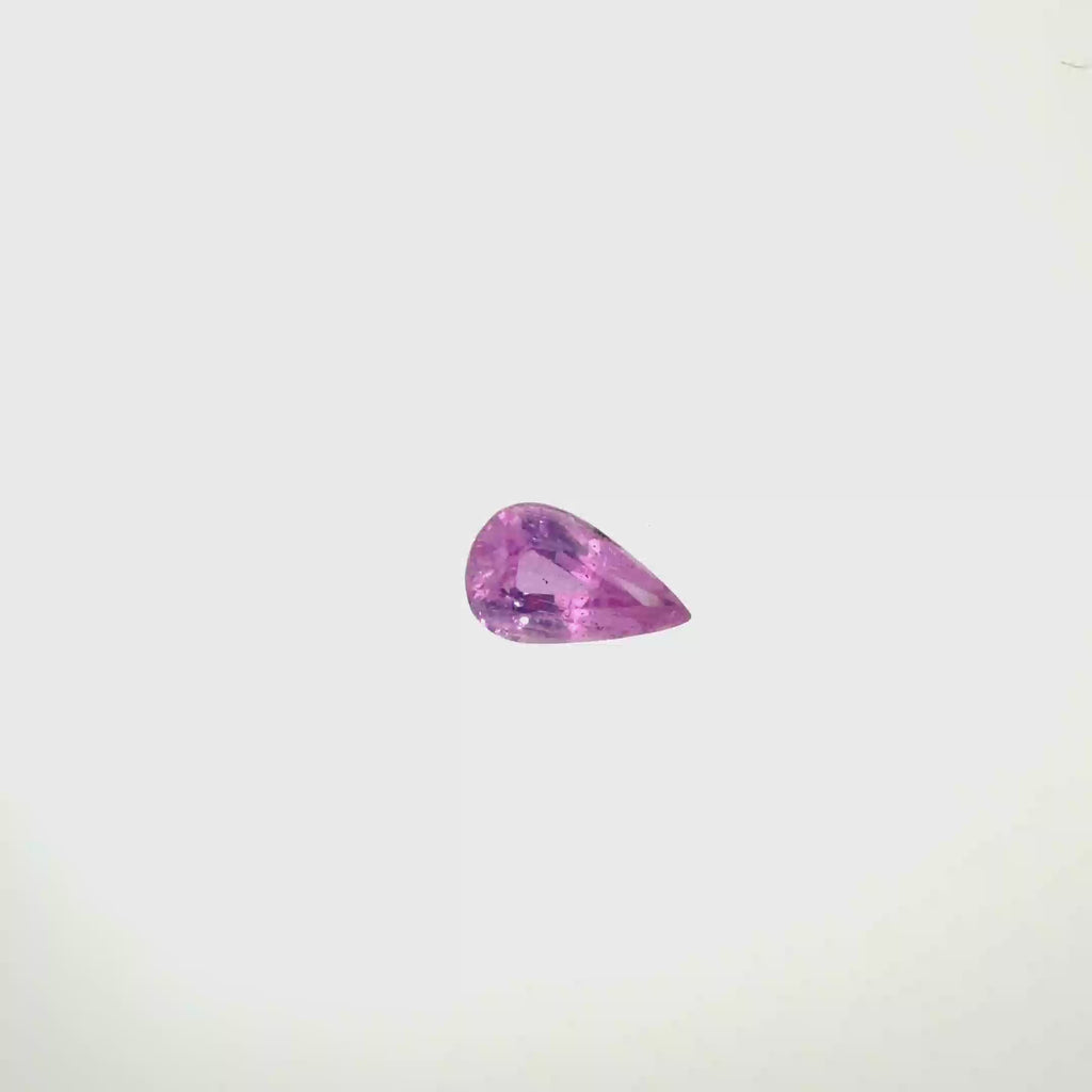 A pear-cut pink gemstone with faceted cuts, centered on a solid white background, spinning 360 degrees.