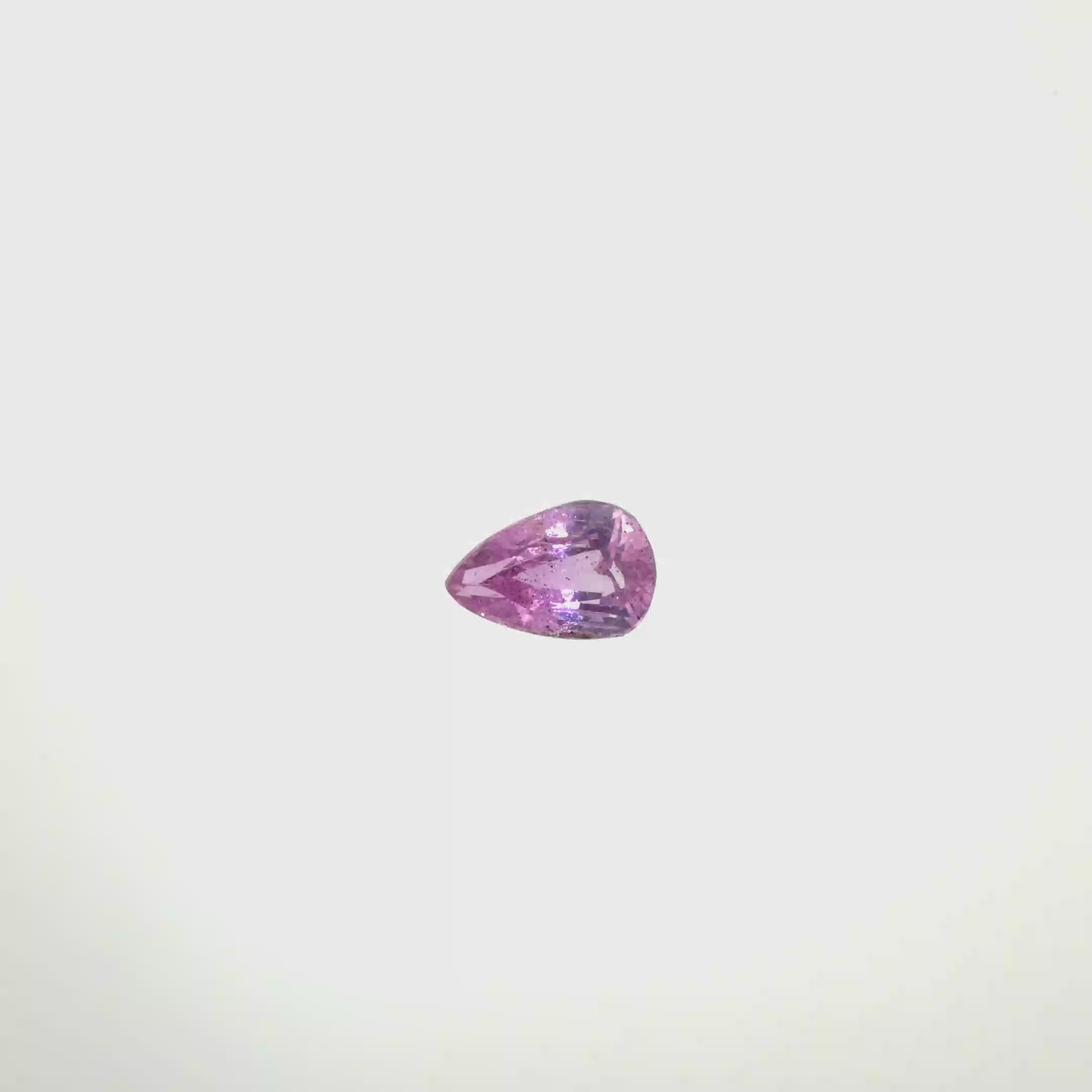A pear-cut pink gemstone with faceted cuts, centered on a solid white background, spinning 360 degrees.